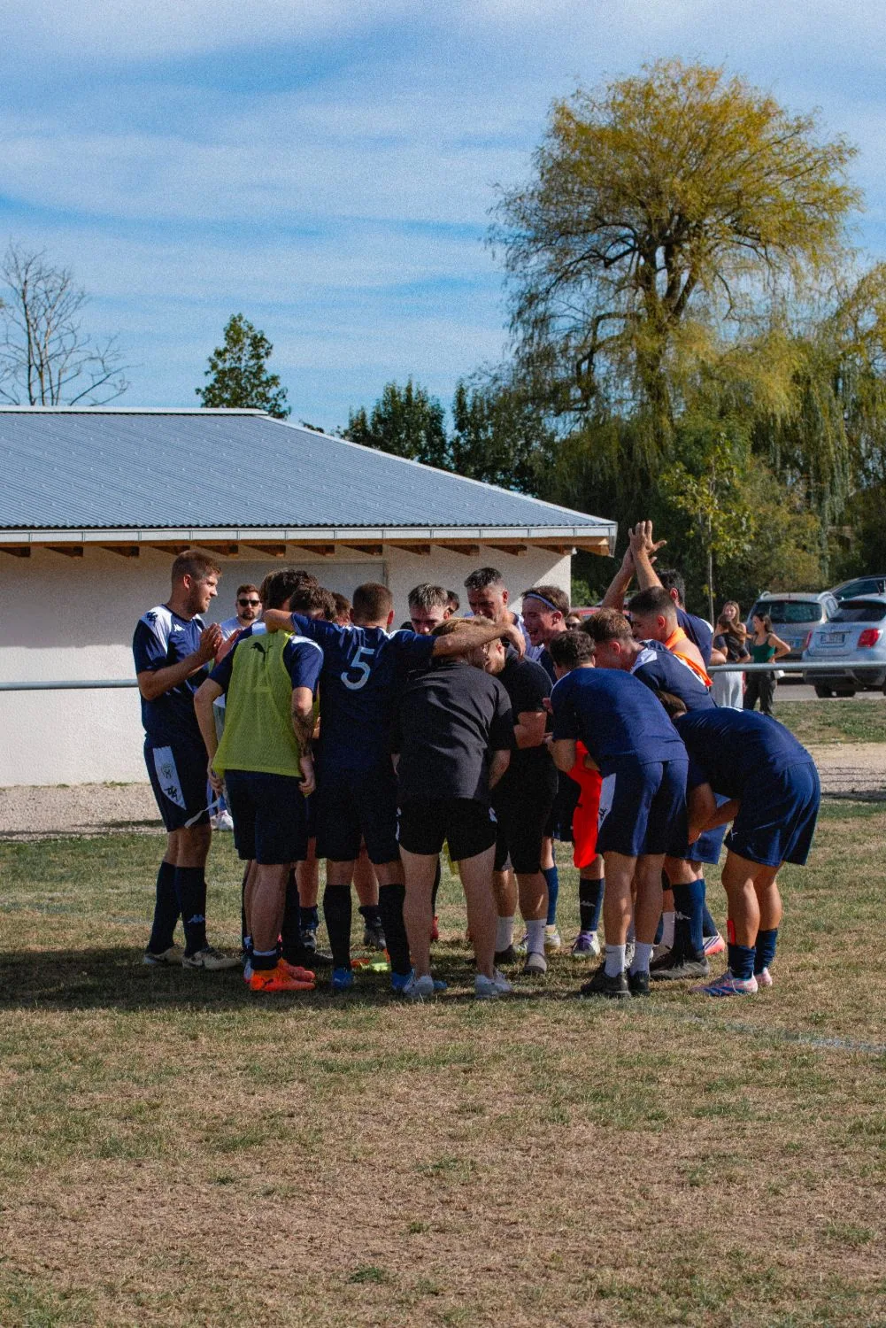 Les joueurs du JRFC réunis en cercle sur la pelouse, bras levés, après la victoire
